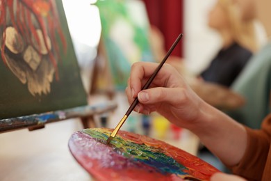 Woman learning to draw with brush on blurred background, closeup