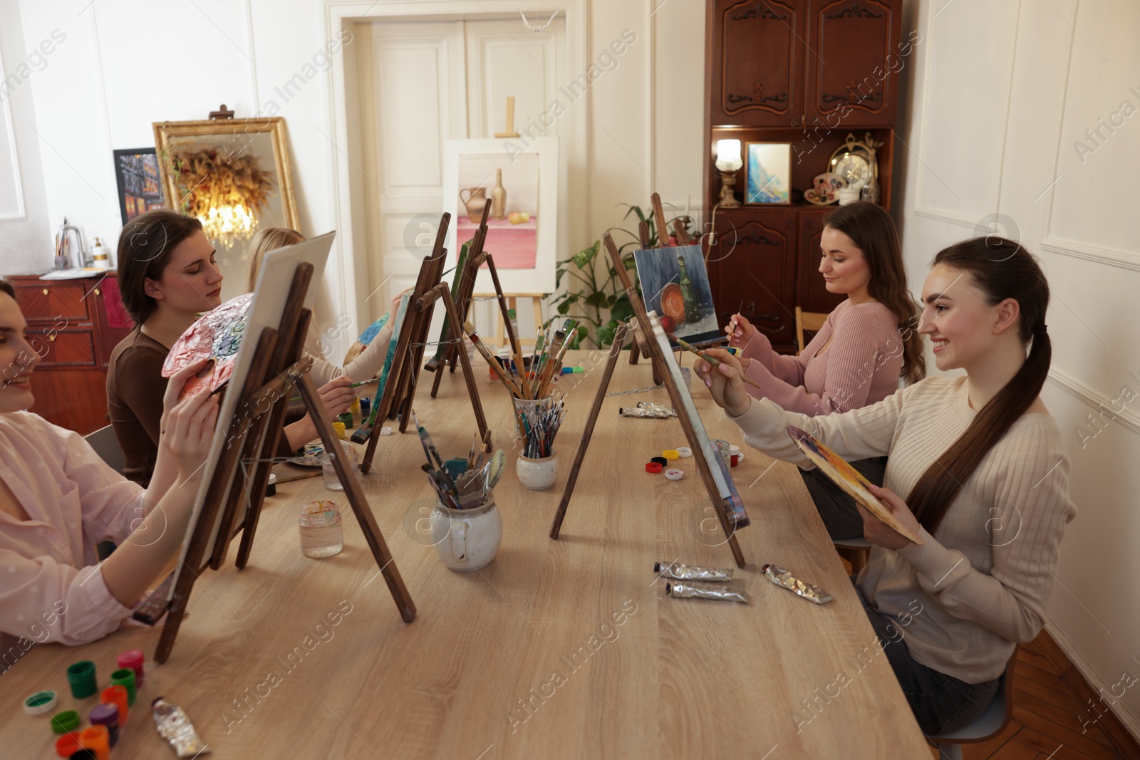 Photo of Group of women learning to draw at wooden table in class