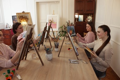 Group of women learning to draw at wooden table in class