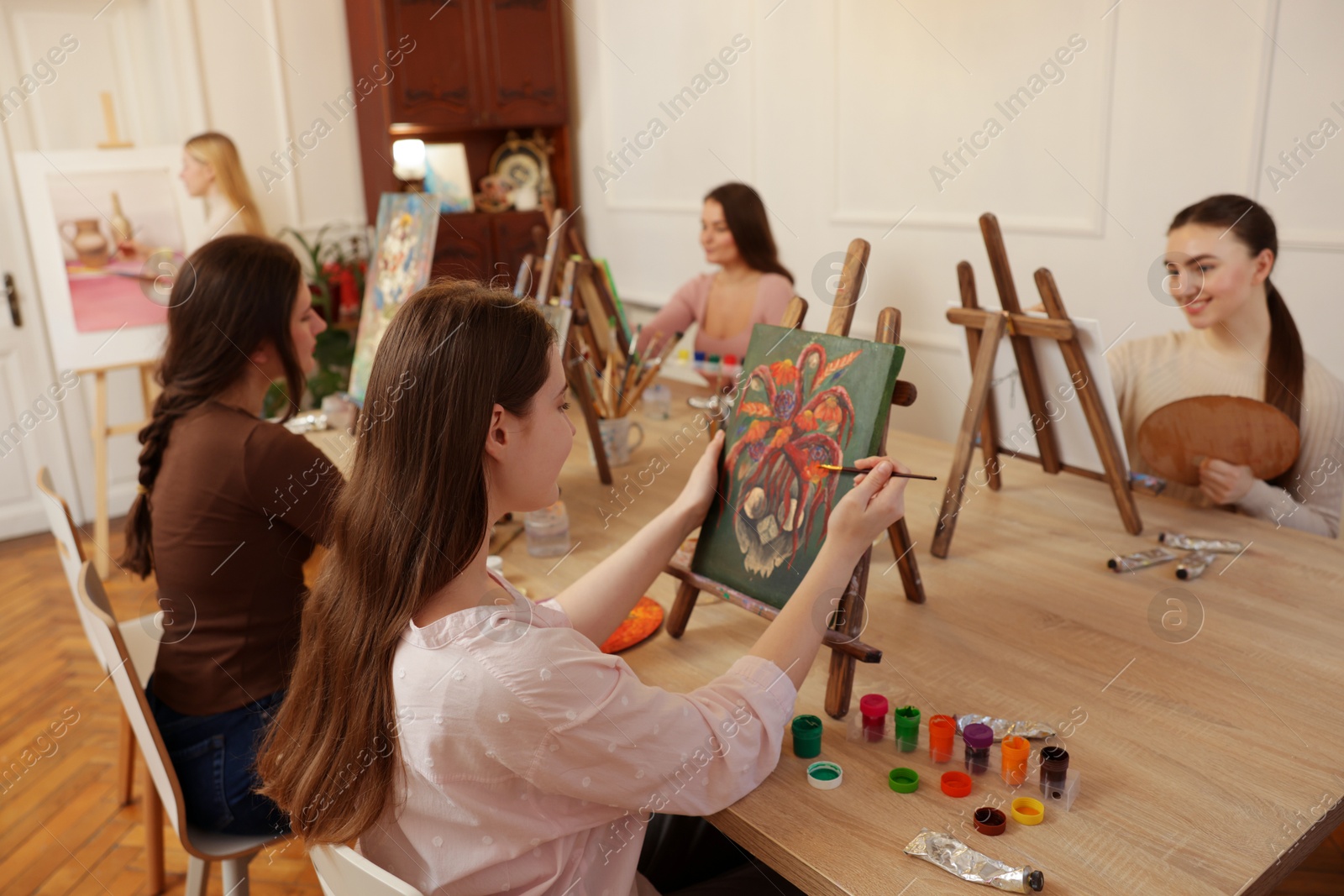 Photo of Group of women learning to draw at wooden table in class