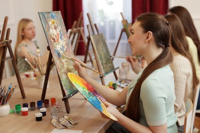 Group of women learning to draw at wooden table in class