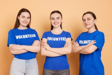 Photo of Portrait of smiling volunteers with crossed arms on beige background