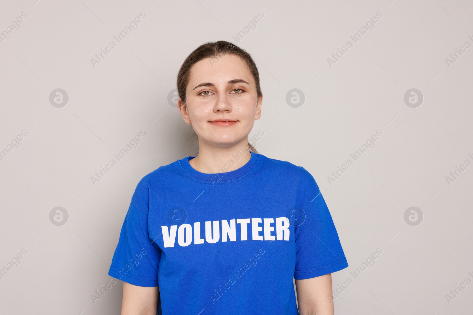 Photo of Portrait of woman in t-shirt with word Volunteer on grey background