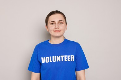 Portrait of woman in t-shirt with word Volunteer on grey background