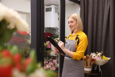 Photo of Business owner with clipboard taking notes in her flower shop