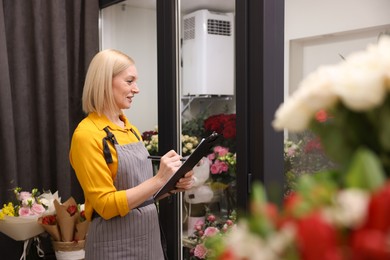 Business owner with clipboard taking notes in her flower shop