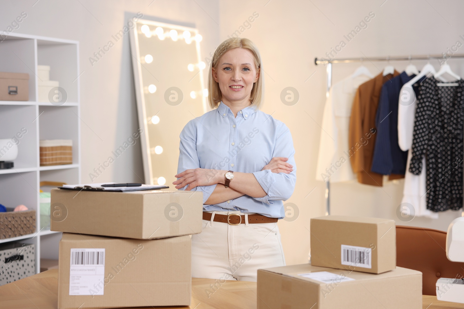 Photo of Business owner near table with parcels in her tailor shop