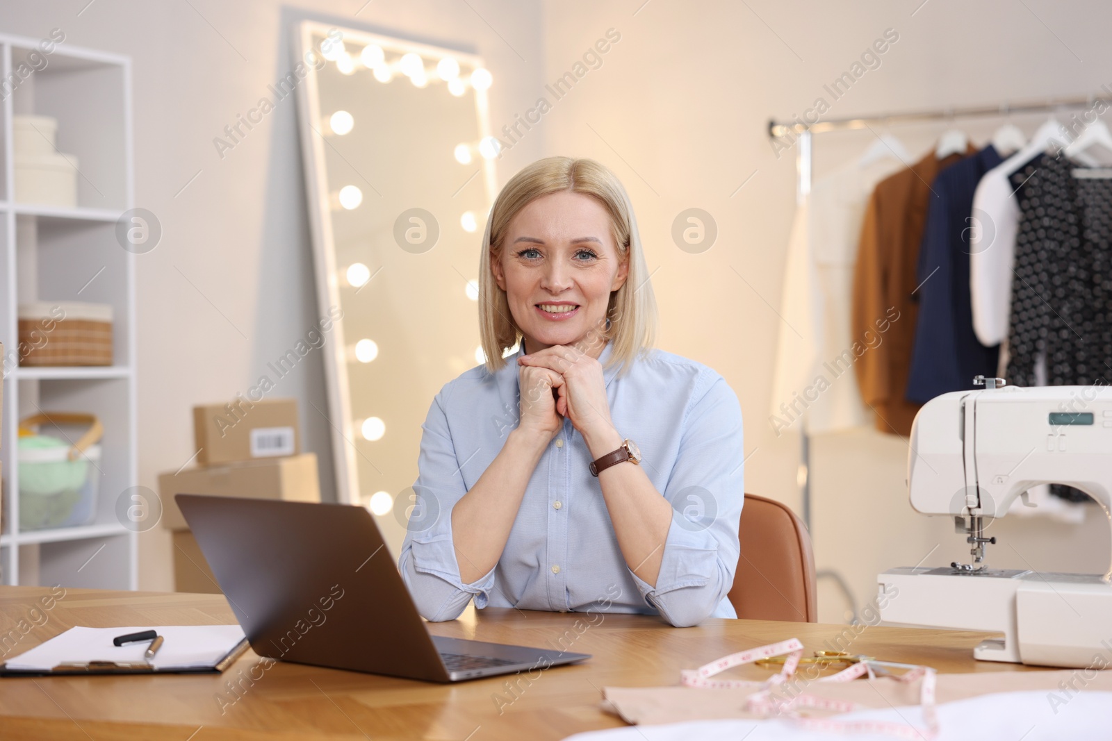 Photo of Business owner at table with laptop in her tailor shop