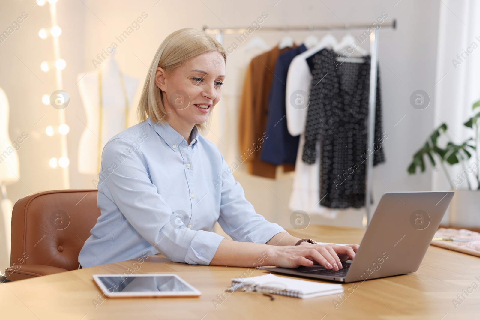 Photo of Business owner working on laptop at table in her tailor shop