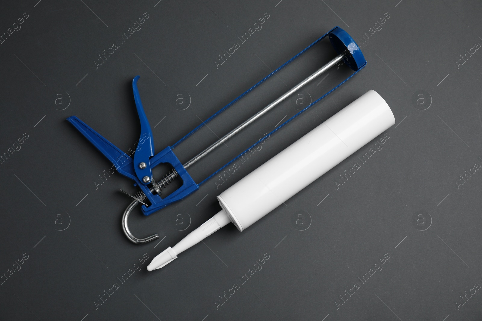 Photo of Glue gun and tube on gray background, flat lay