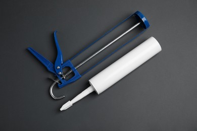 Glue gun and tube on gray background, flat lay