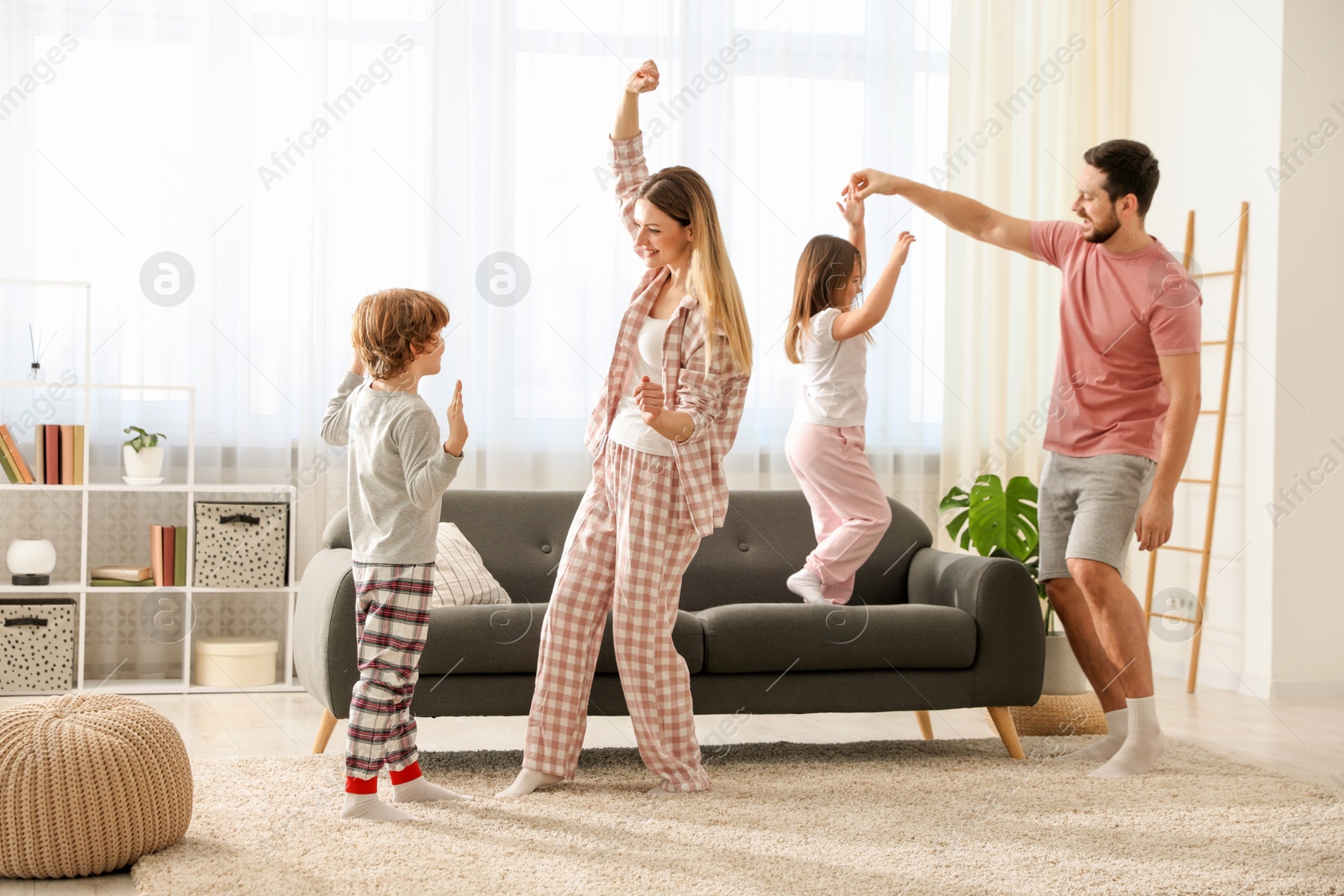 Photo of Happy family wearing stylish pajamas having fun at home