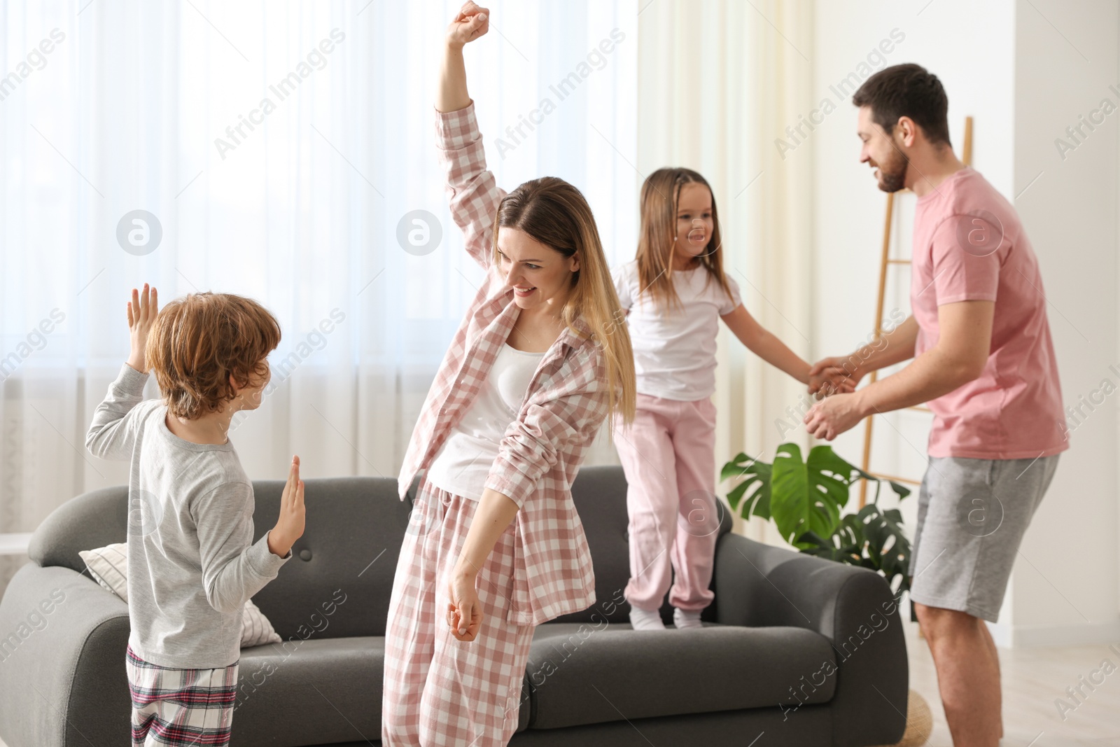 Photo of Happy family wearing stylish pajamas having fun at home