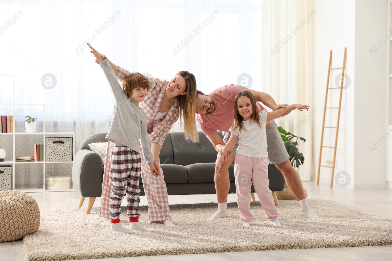 Photo of Happy family wearing stylish pajamas having fun at home