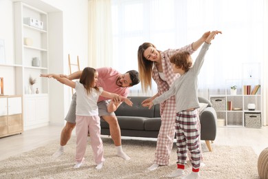 Photo of Happy family wearing stylish pajamas having fun at home