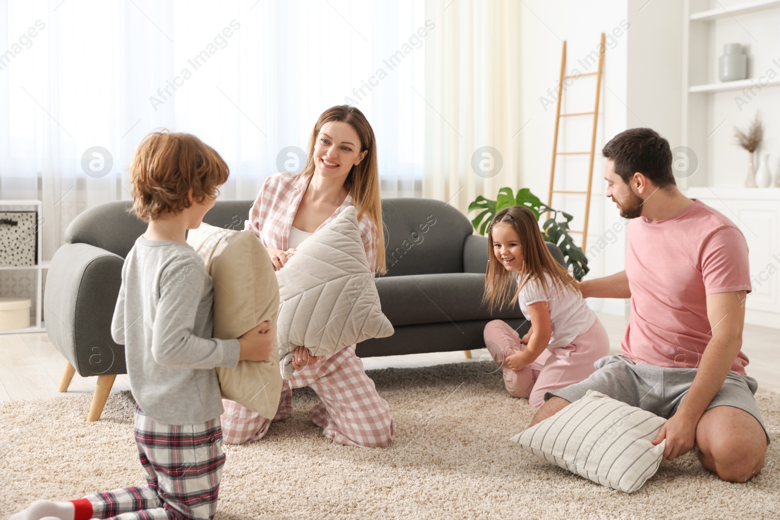 Photo of Happy family wearing pajamas having pillow fight at home