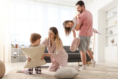 Happy family wearing pajamas having pillow fight at home