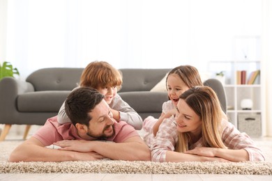 Family portrait of happy parents and their children wearing stylish pajamas on floor at home