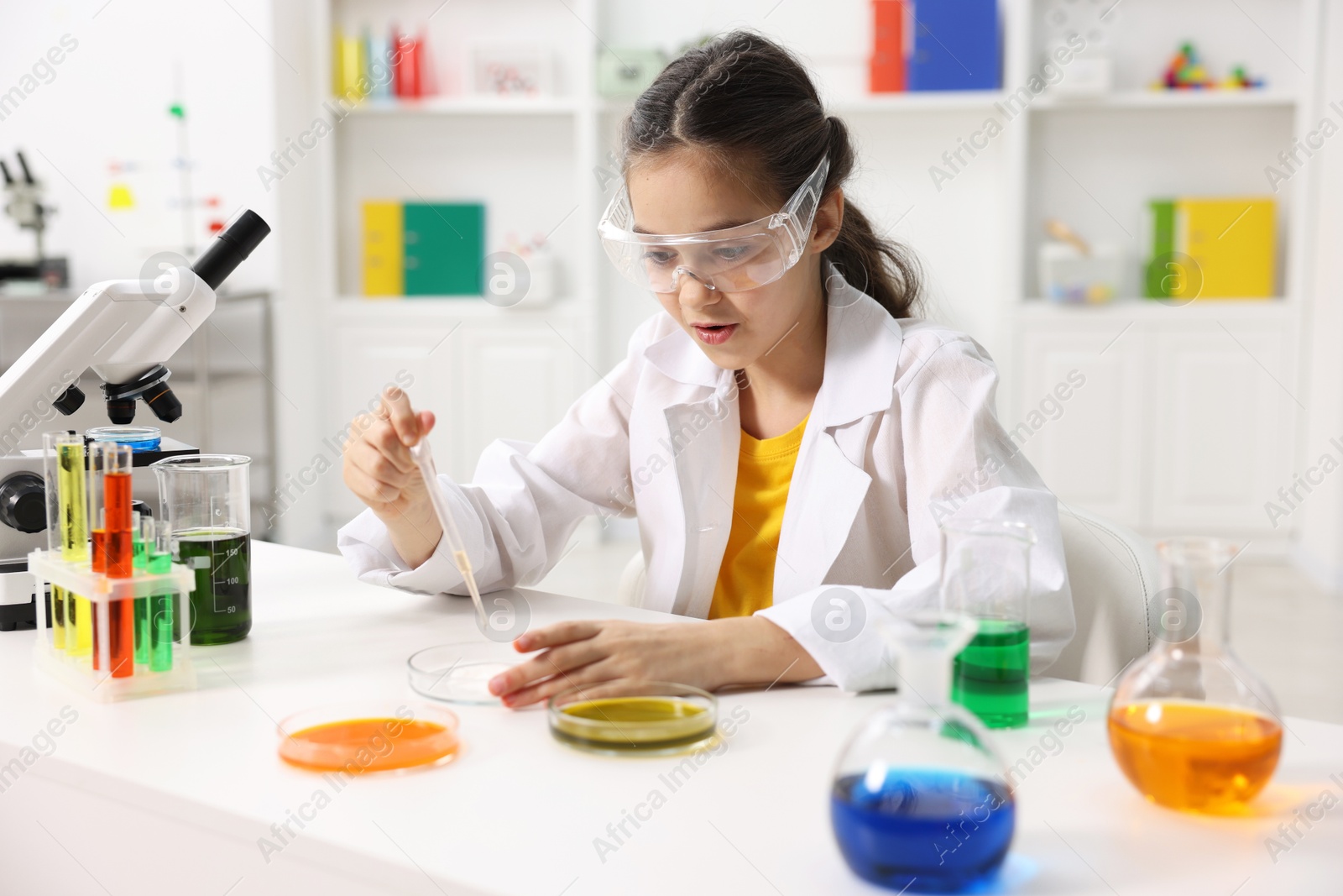 Photo of Little girl doing chemical experiment at desk indoors