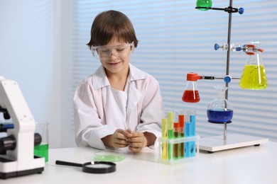 Little boy doing chemical experiment at desk indoors