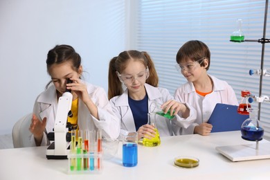 Children doing chemical experiment at desk indoors