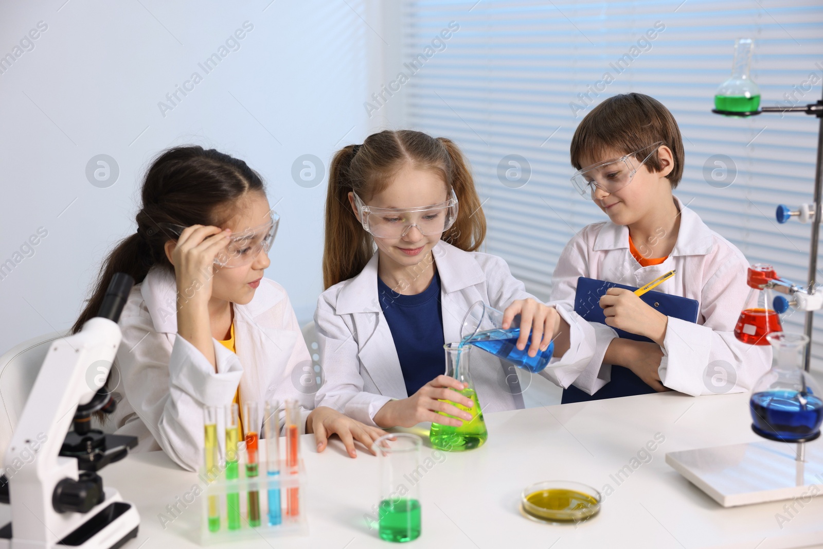 Photo of Children doing chemical experiment at desk indoors