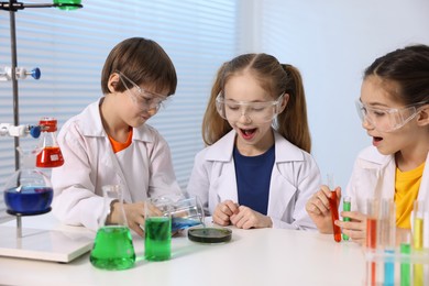 Children doing chemical experiment at desk indoors