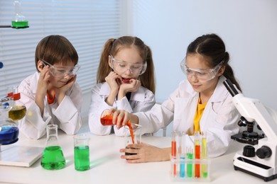 Children doing chemical experiment at desk indoors