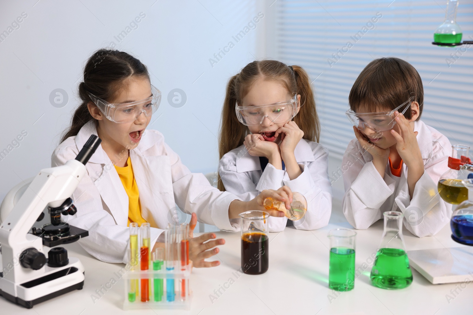 Photo of Children doing chemical experiment at desk indoors