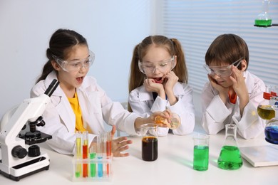 Children doing chemical experiment at desk indoors