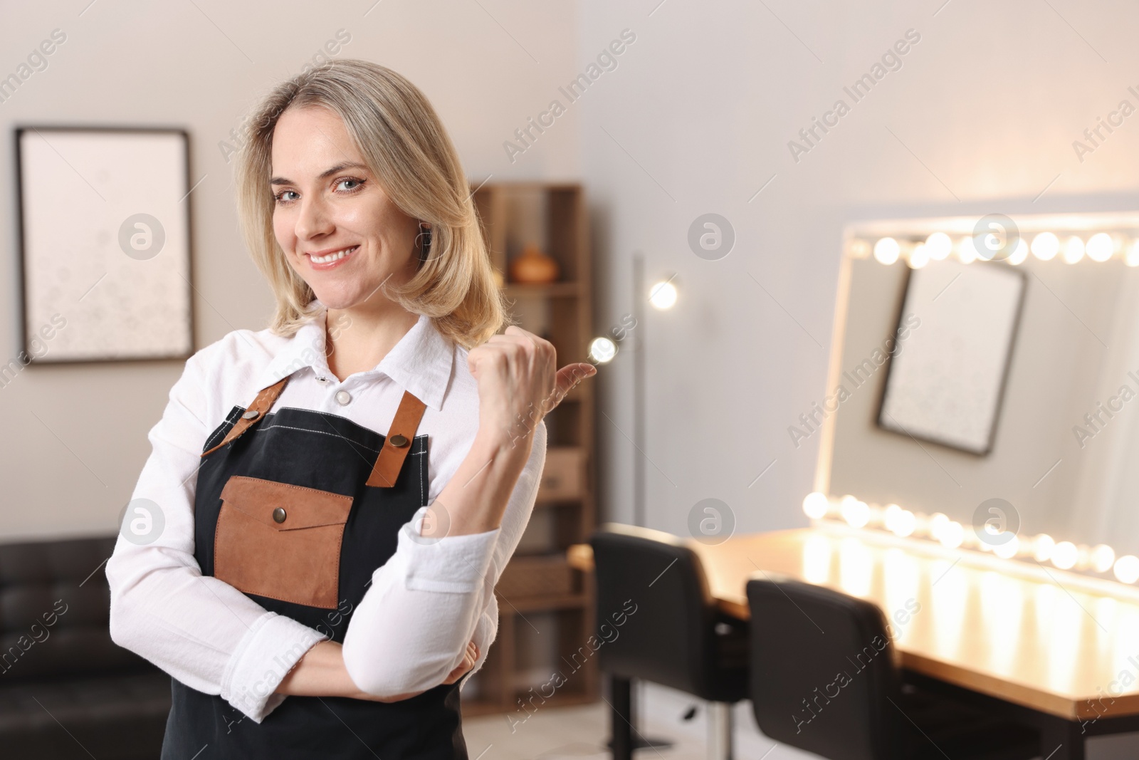 Photo of Portrait of smiling hairdresser in beauty salon, space for text