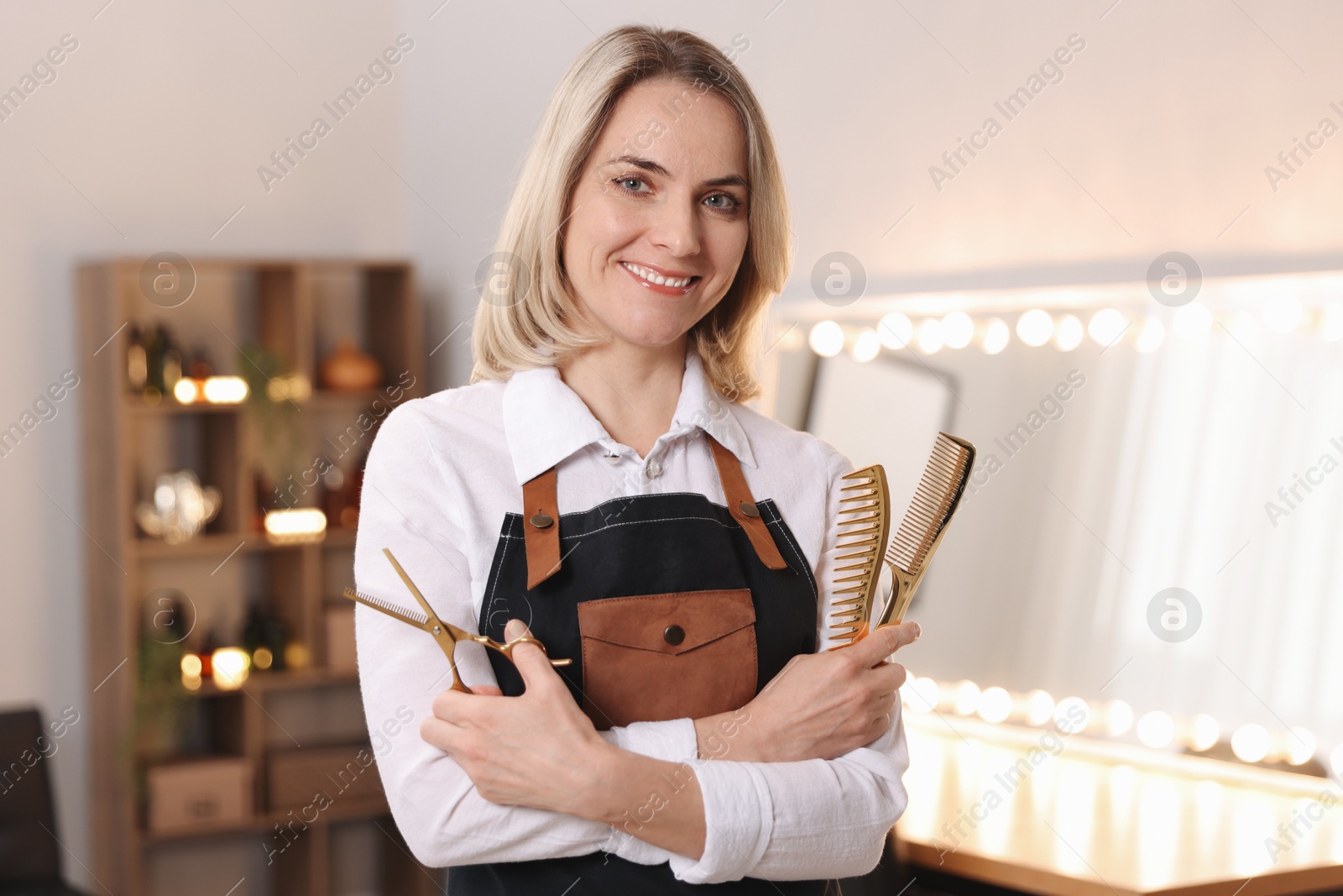 Photo of Smiling hairdresser with combs and scissors in beauty salon