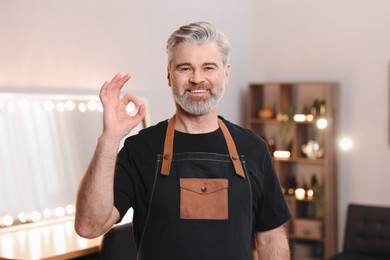 Smiling hairdresser showing OK gesture in beauty salon