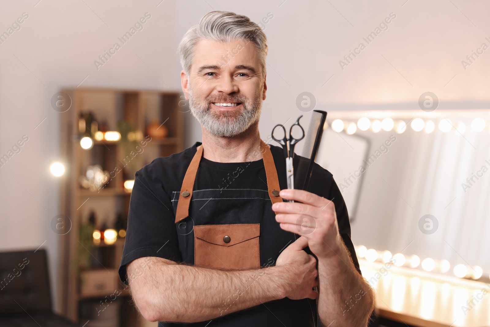 Photo of Smiling hairdresser with comb and scissors in beauty salon