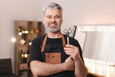 Smiling hairdresser with comb and scissors in beauty salon