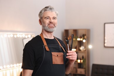 Photo of Smiling hairdresser with comb and scissors in beauty salon