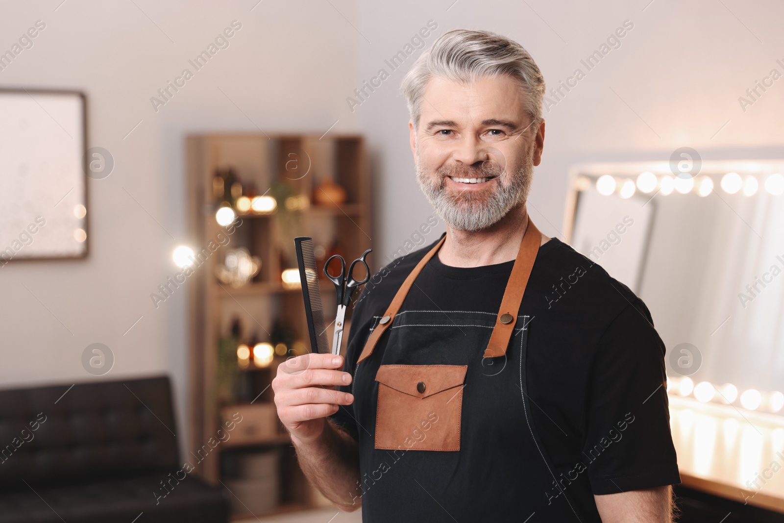 Photo of Smiling hairdresser with comb and scissors in beauty salon