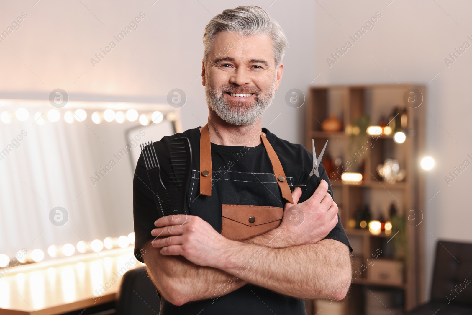 Photo of Smiling hairdresser with combs and scissors in beauty salon