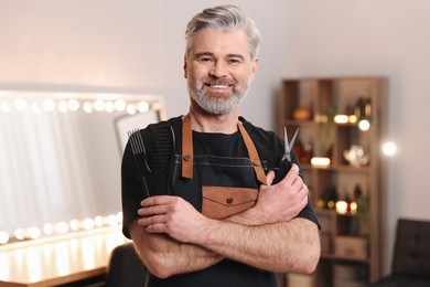 Smiling hairdresser with combs and scissors in beauty salon