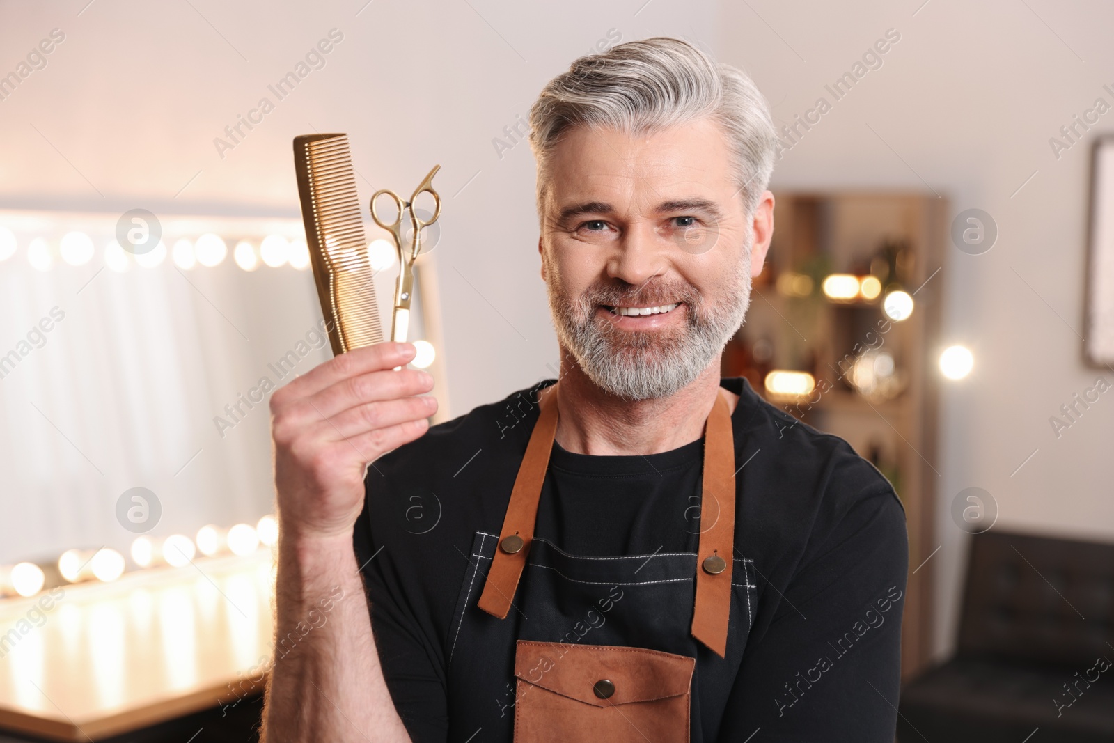 Photo of Smiling hairdresser with comb and scissors in beauty salon