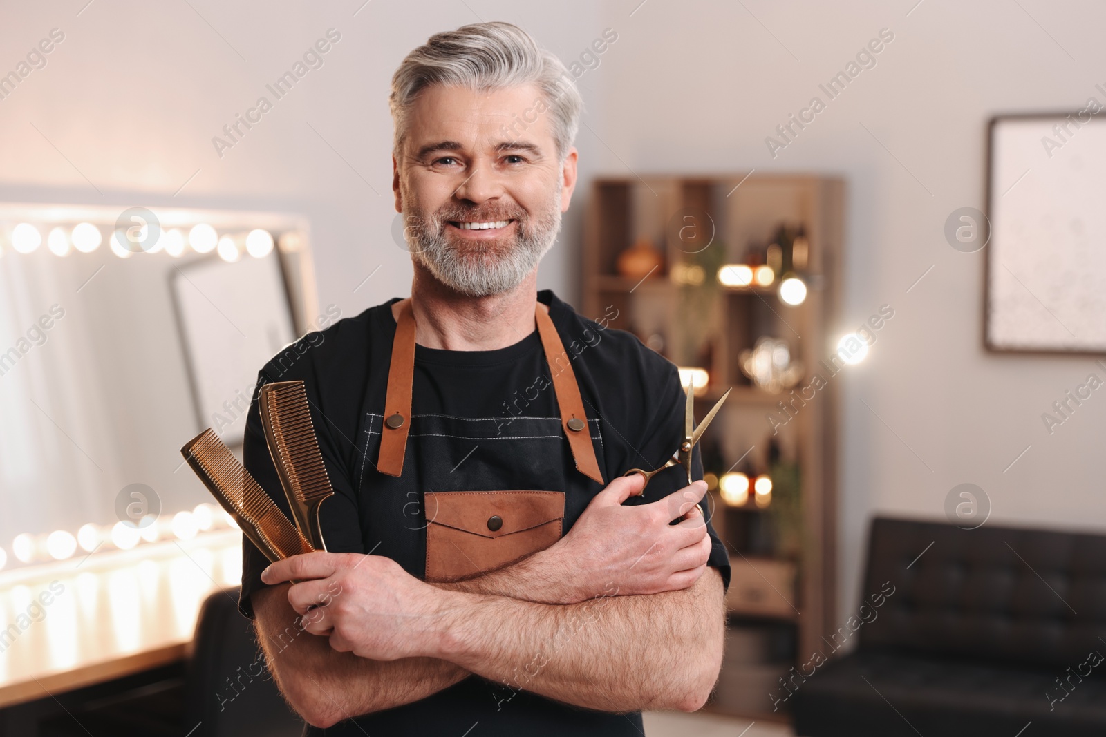 Photo of Smiling hairdresser with combs and scissors in beauty salon