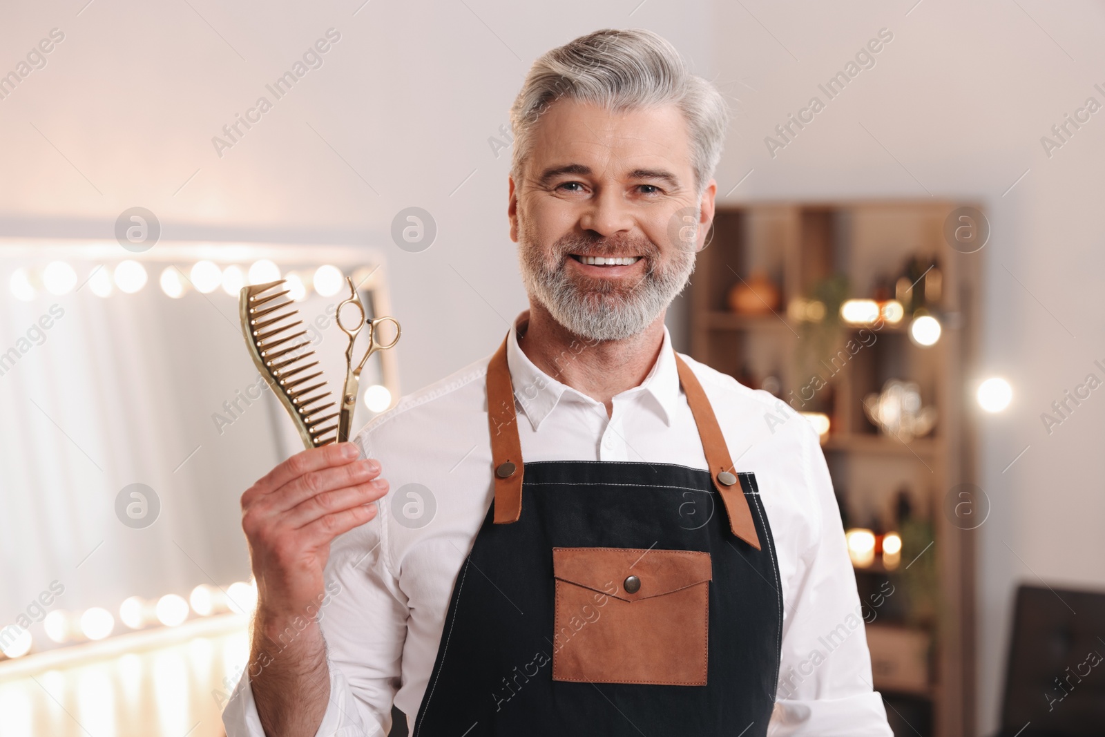 Photo of Smiling hairdresser with scissors and comb in beauty salon