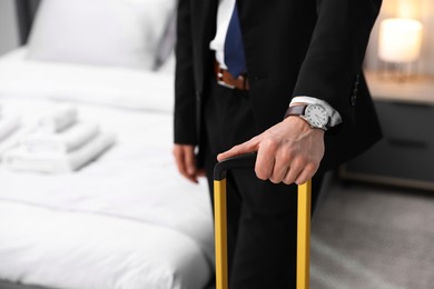 Photo of Businessman with suitcase in hotel room, closeup