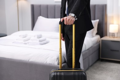 Photo of Businessman with suitcase in hotel room, closeup