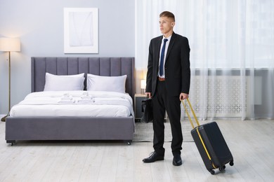 Businessman with suitcase and briefcase in hotel room