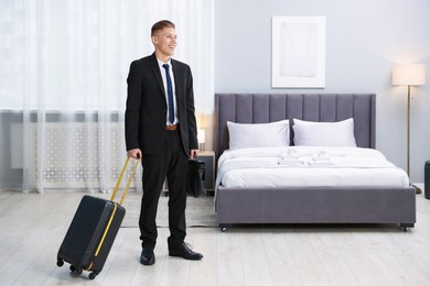 Businessman with suitcase and briefcase in hotel room