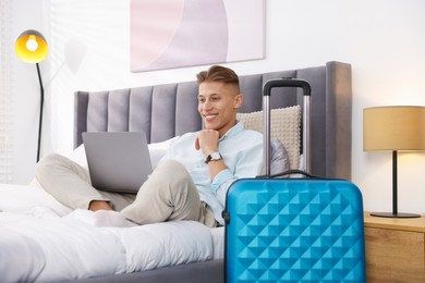 Photo of Man with laptop on bed in his hotel room