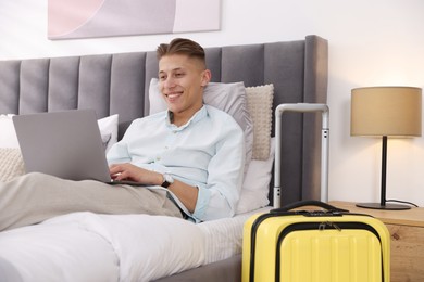 Man with laptop on bed in his hotel room