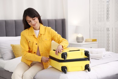 Woman unpacking suitcase on bed in hotel room