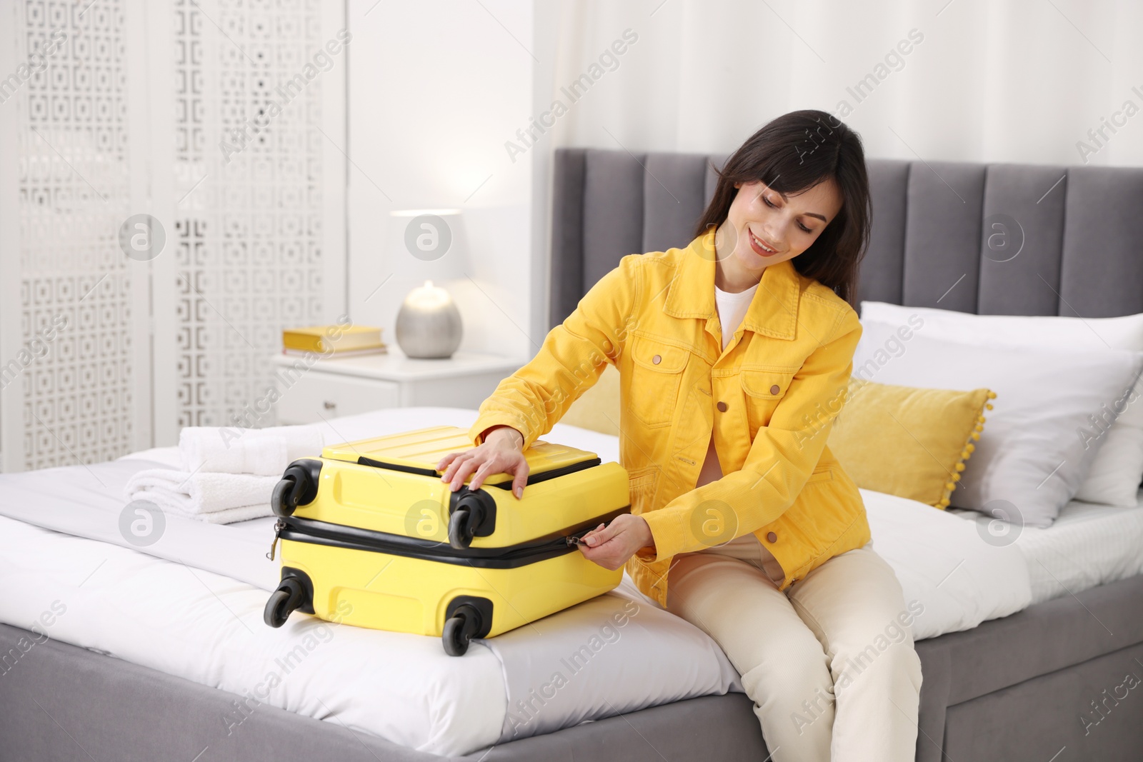 Photo of Woman unpacking suitcase on bed in hotel room